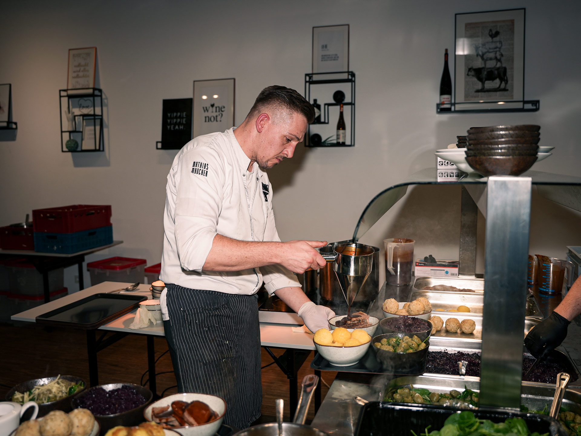 Ein Koch mit konzentriertem Gesichtsausdruck serviert Speisen in einer modernen Küche