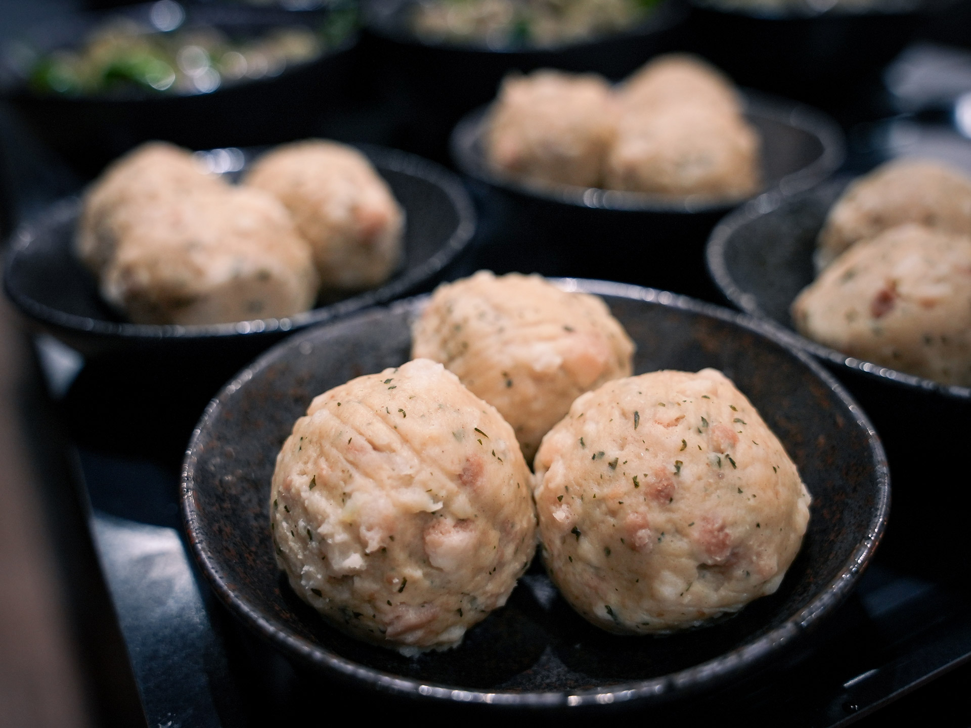 Zwei helle, würzige Semmelknödel in einer dunklen Schüssel, locker serviert