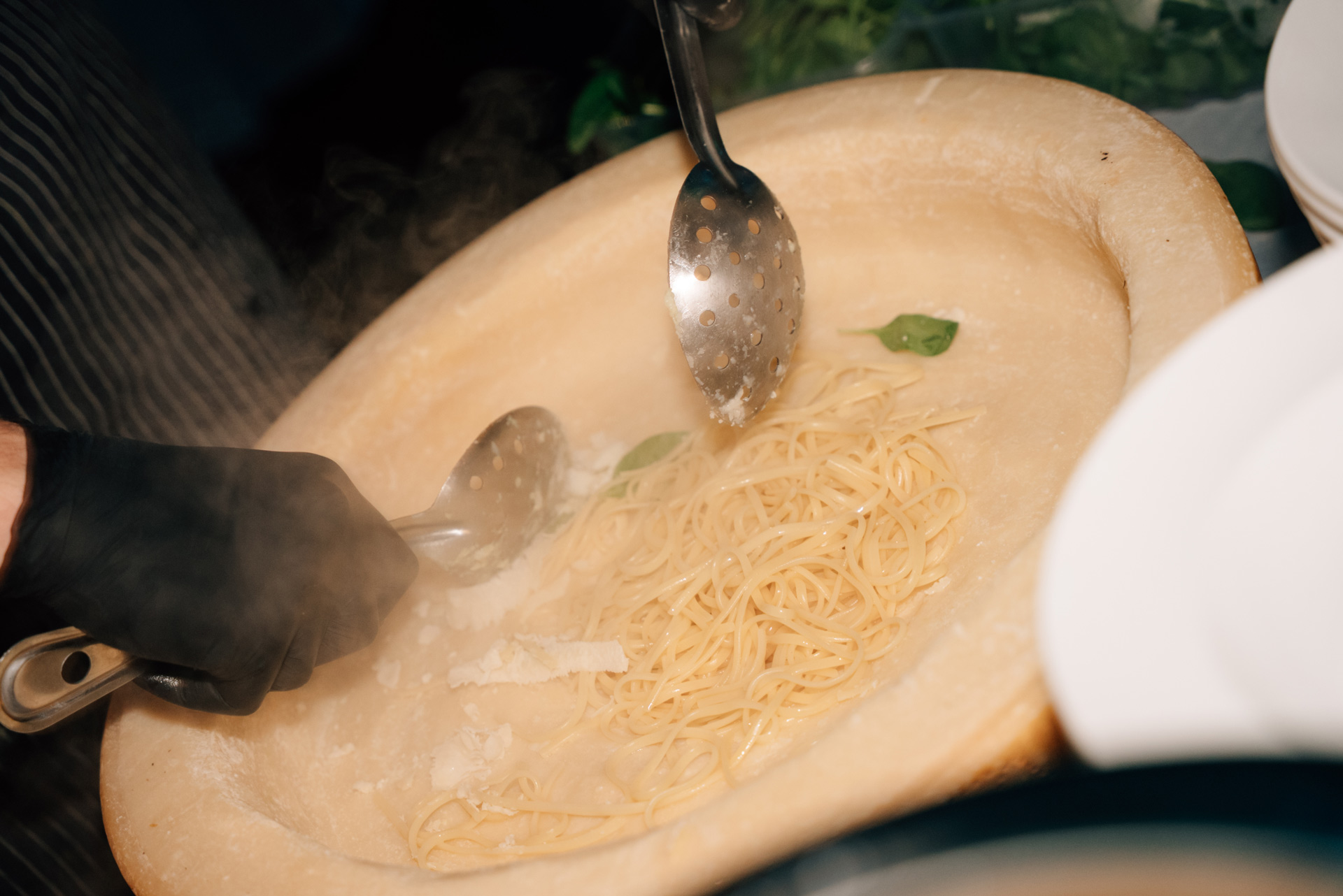 Frisch gekochte Spaghetti werden mit Parmesan in einem großen Käselaib vermischt