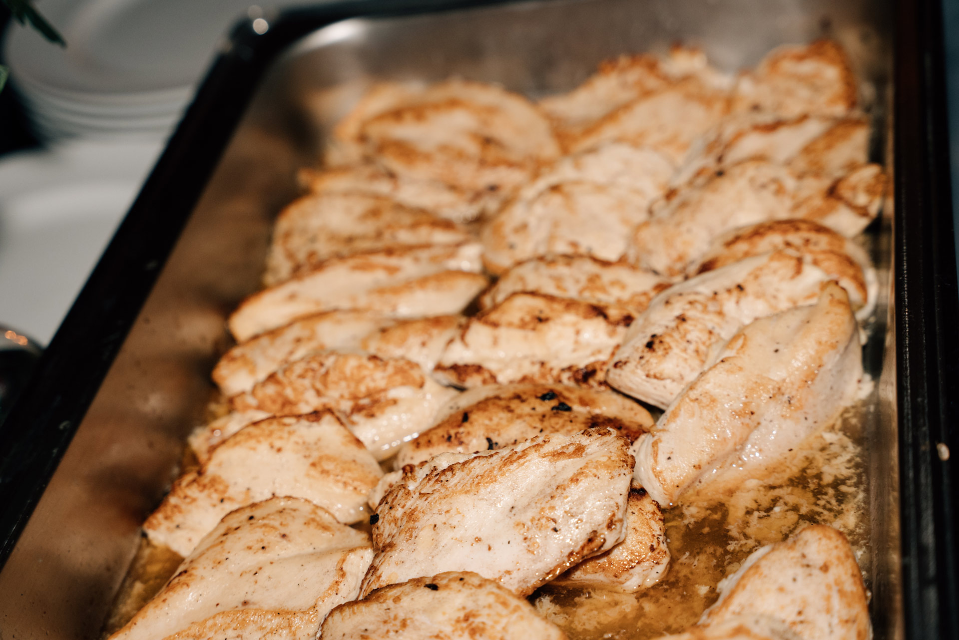 Mehrere goldbraune Hühnchenbrustfilets liegen saftig nebeneinander in einer Metallschale