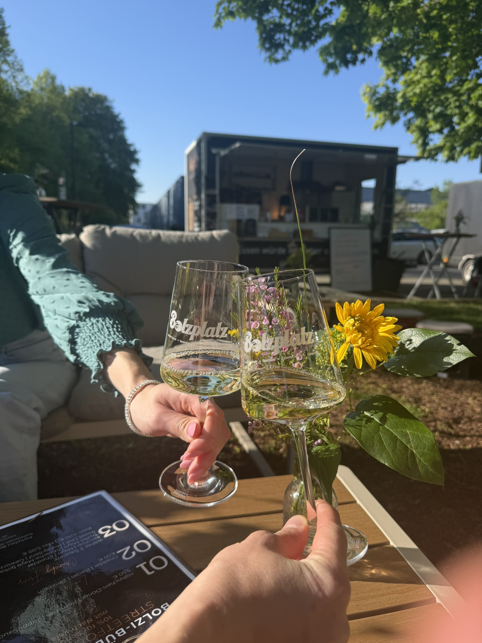 Zwei Personen stossen mit Weisswein an einem sonnigen Sommertag im Freien an